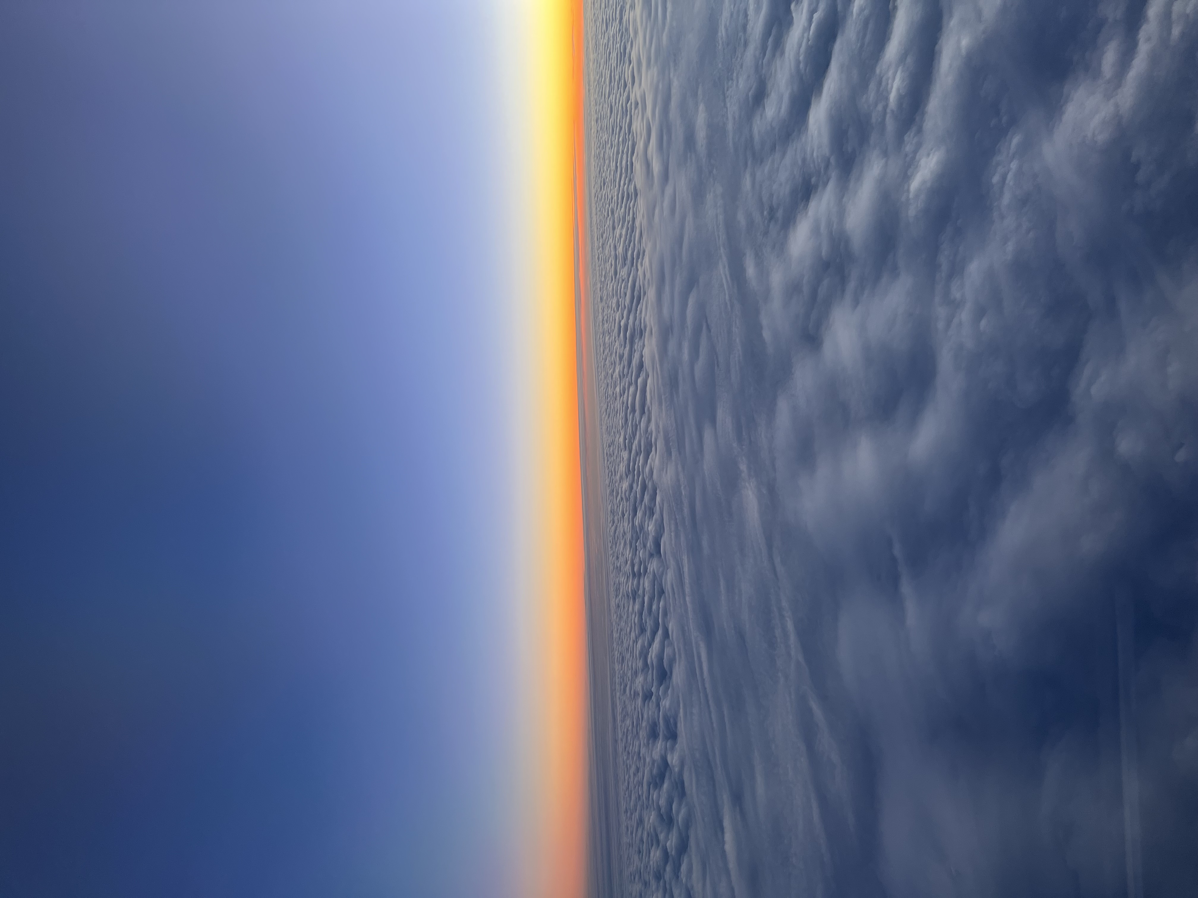 Sunset gradient from orange to deep blue above a solid cloud deck
